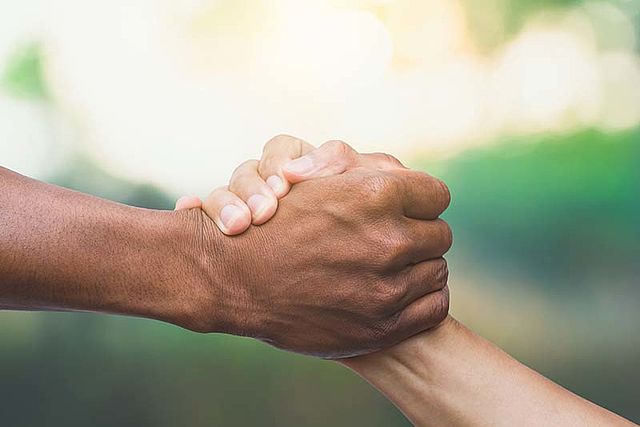 Eine starke Hand greift eine schwächere Hand zur Unterstützung